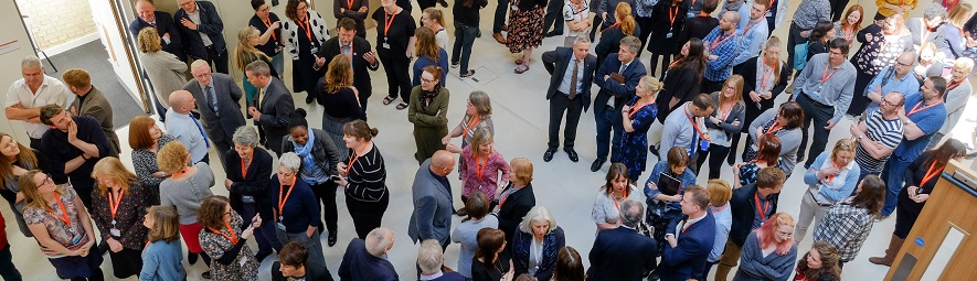 Large crowd of Cambridge colleagues chatting in small groups